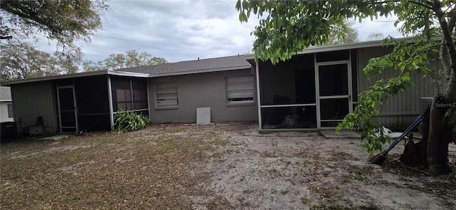 rear view of property featuring a sunroom and stucco siding