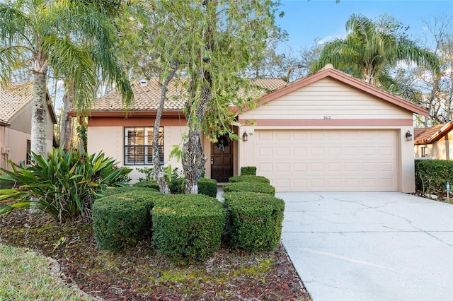 view of front of home with an attached garage, driveway, a tiled roof, and stucco siding