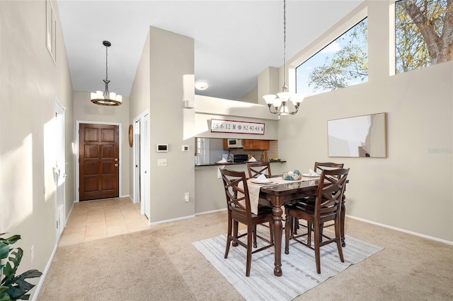 carpeted dining space featuring a chandelier, a high ceiling, and baseboards