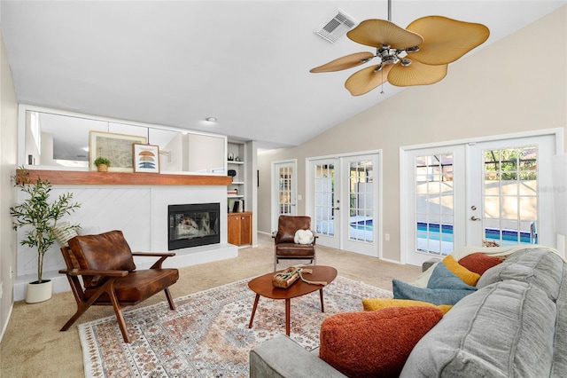 living room featuring visible vents, a tile fireplace, lofted ceiling, light colored carpet, and french doors