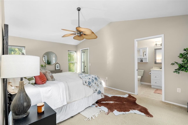 bedroom with lofted ceiling, light carpet, a ceiling fan, baseboards, and ensuite bath