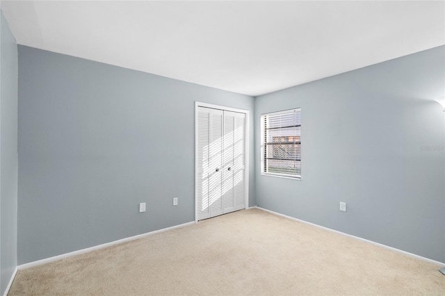 empty room featuring light carpet and baseboards