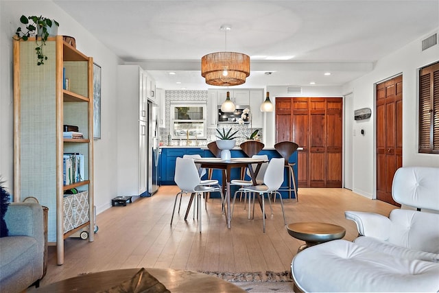 dining area with light wood-type flooring, baseboards, and visible vents