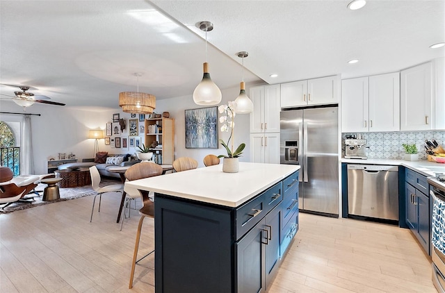 kitchen featuring stainless steel appliances, open floor plan, white cabinets, and blue cabinetry