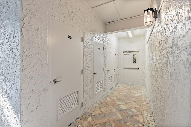 hallway featuring visible vents and a textured wall