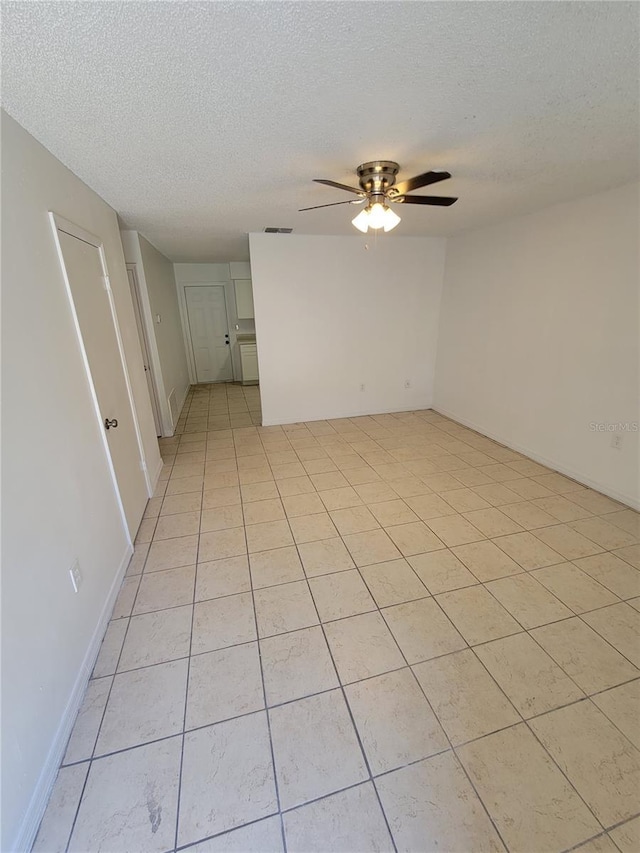 unfurnished room with visible vents, a textured ceiling, and a ceiling fan