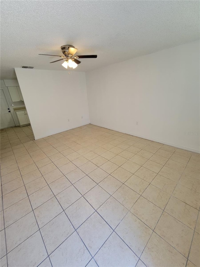 empty room with visible vents, a textured ceiling, and a ceiling fan