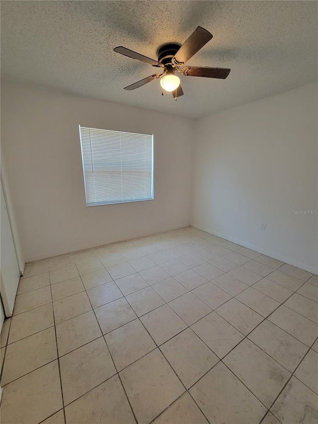 unfurnished room featuring a textured ceiling, light tile patterned flooring, and ceiling fan