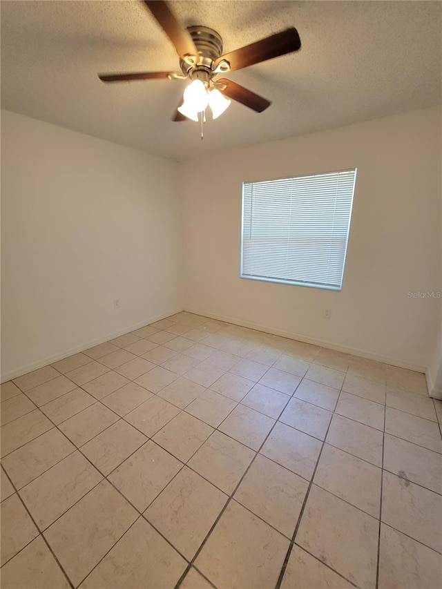 unfurnished room with baseboards, a textured ceiling, light tile patterned flooring, and a ceiling fan