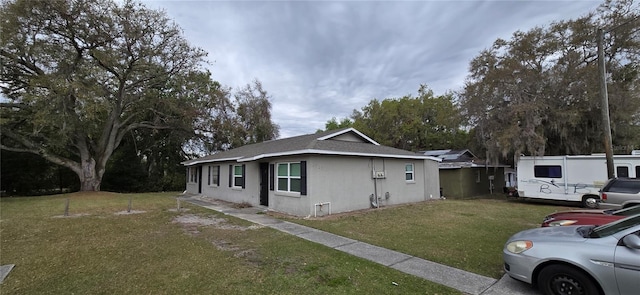 view of side of home featuring stucco siding and a lawn