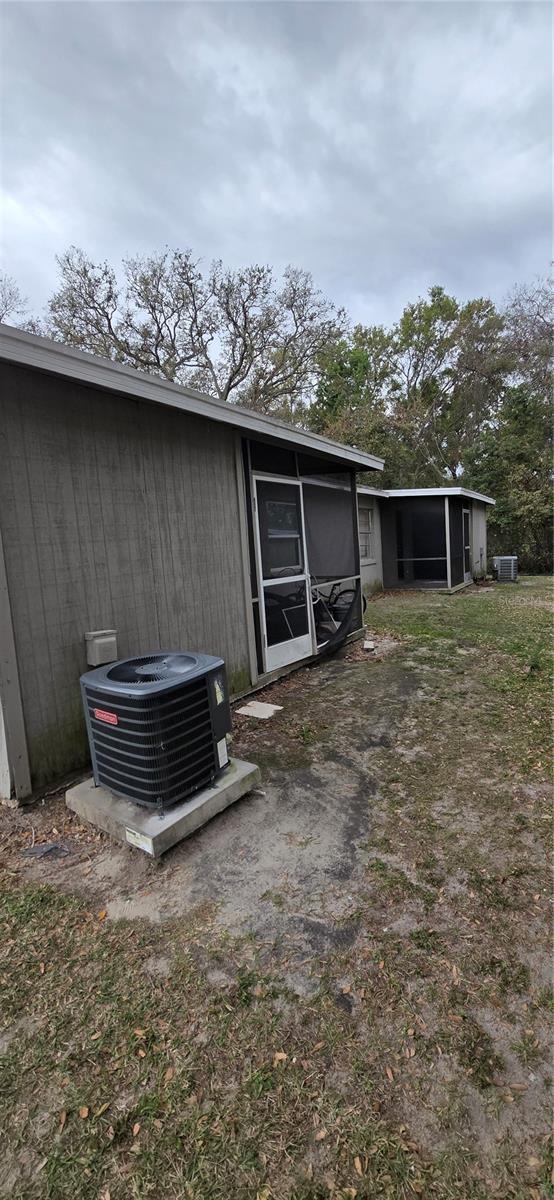 rear view of property featuring central AC unit and a sunroom