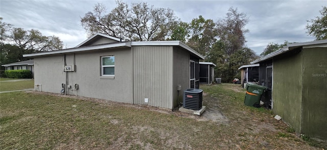 view of side of home featuring central AC unit and a lawn