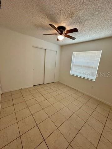 unfurnished room with light tile patterned floors, a textured ceiling, baseboards, and ceiling fan