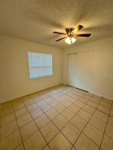 spare room with ceiling fan, a textured ceiling, and light tile patterned flooring