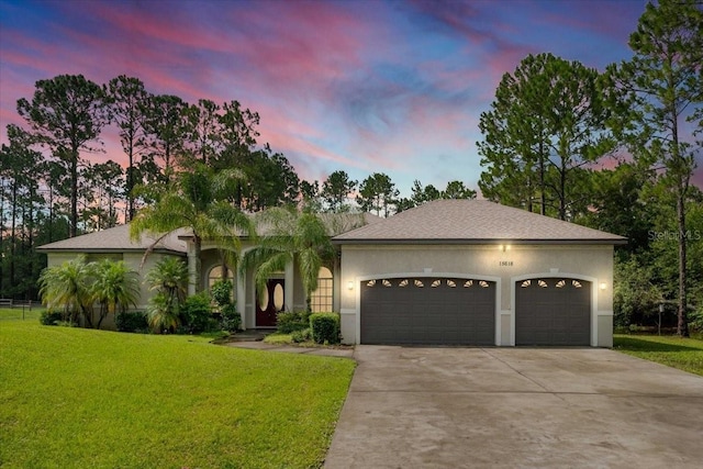 view of front of property featuring driveway, stucco siding, a garage, and a front yard