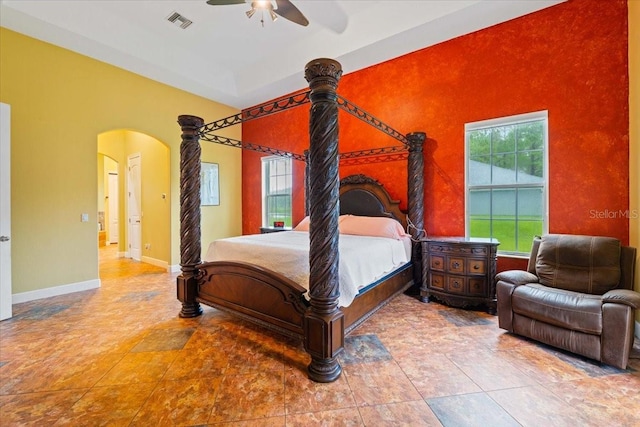 bedroom with baseboards, multiple windows, visible vents, and arched walkways