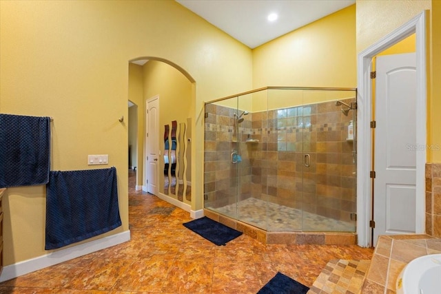 full bathroom with a shower stall, a bathing tub, and baseboards