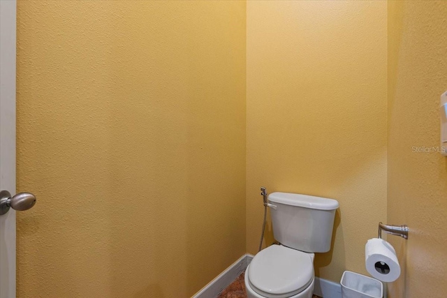 bathroom with baseboards and toilet