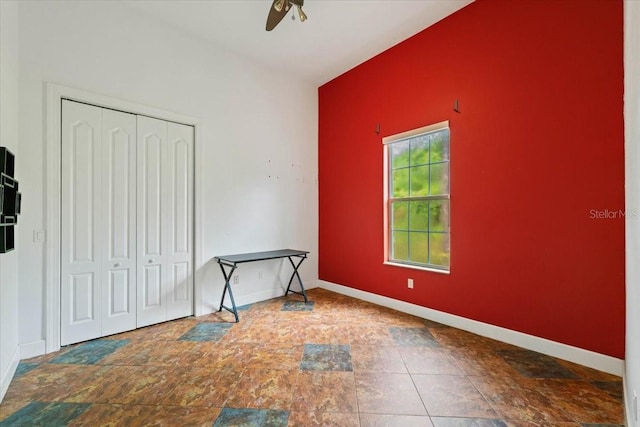 bedroom with stone finish floor, ceiling fan, baseboards, and a closet