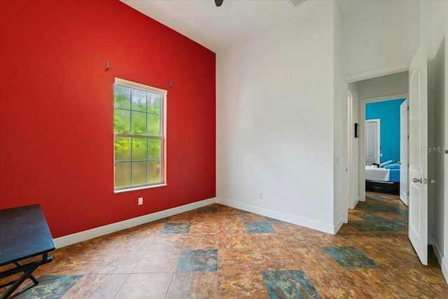 interior space featuring lofted ceiling, stone finish flooring, and baseboards