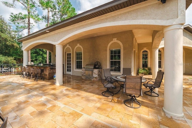 view of patio with outdoor dining space, area for grilling, a grill, and outdoor wet bar