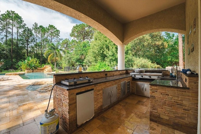 view of patio / terrace featuring a grill, an outdoor pool, a sink, and area for grilling