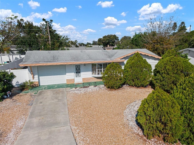 ranch-style home featuring concrete driveway, fence, and an attached garage