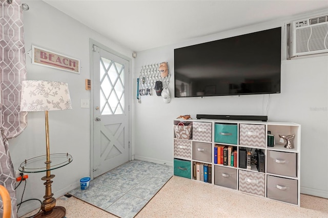 foyer featuring a wall mounted AC, baseboards, and speckled floor