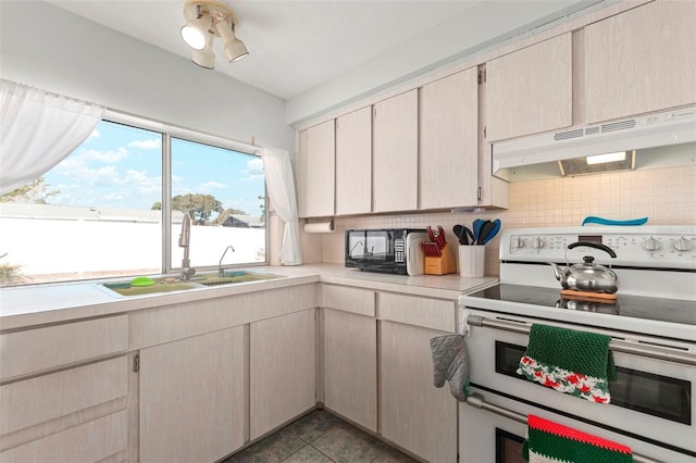 kitchen with range with two ovens, tasteful backsplash, light countertops, a sink, and under cabinet range hood