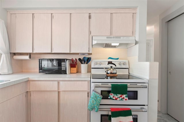 kitchen featuring black microwave, range with two ovens, under cabinet range hood, light countertops, and tasteful backsplash