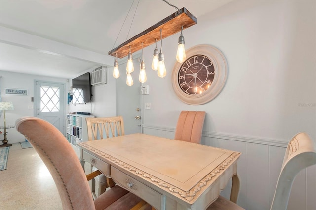 dining space with beam ceiling, a wainscoted wall, a decorative wall, an AC wall unit, and speckled floor