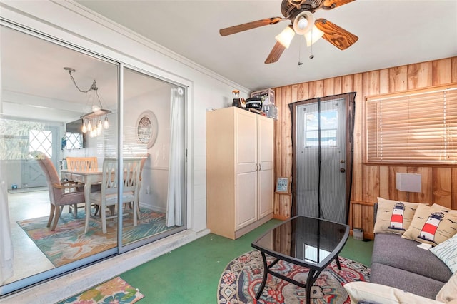 living room featuring wood walls and ceiling fan with notable chandelier