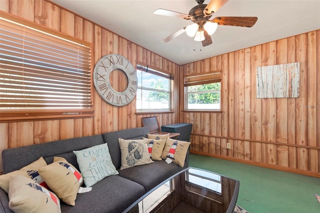 living area with carpet floors, a ceiling fan, and wooden walls