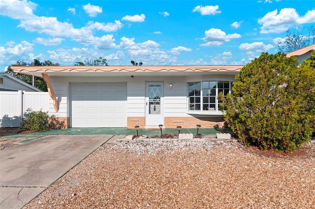 single story home with driveway, an attached garage, and fence