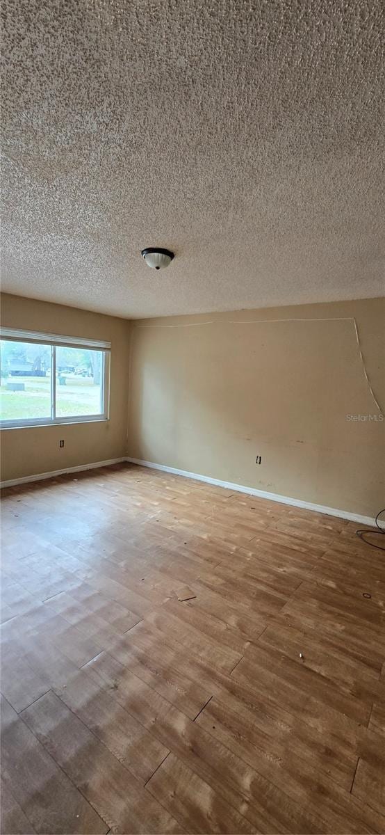 empty room with wood finished floors, baseboards, and a textured ceiling