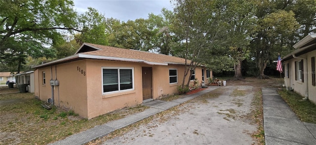 view of side of home featuring roof with shingles and stucco siding