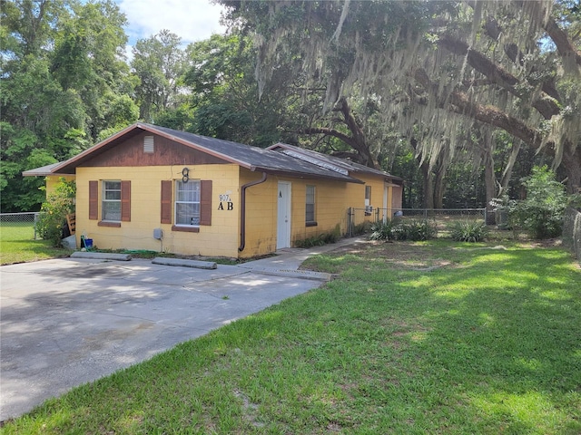 view of front of house featuring a front lawn, concrete block siding, and fence