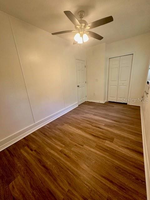 unfurnished bedroom with ceiling fan, dark wood-type flooring, and baseboards