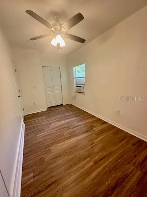 unfurnished bedroom featuring cooling unit, dark wood finished floors, a ceiling fan, and baseboards