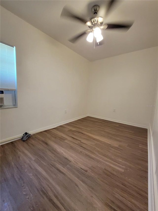 spare room featuring ceiling fan, cooling unit, wood finished floors, and baseboards