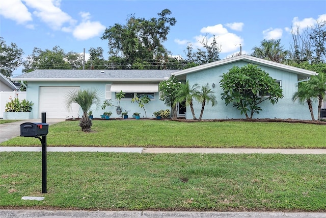 view of front of home featuring a garage, brick siding, driveway, and a front yard