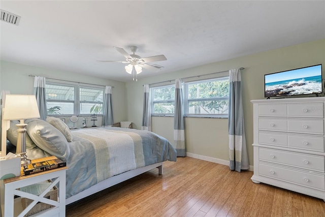 bedroom with ceiling fan, light wood-type flooring, visible vents, and baseboards