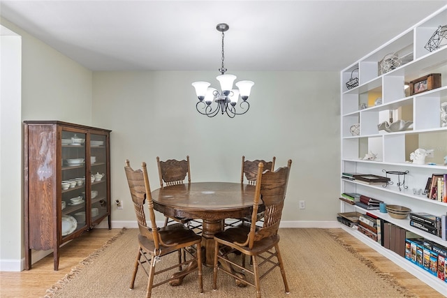 dining room with a chandelier, light wood finished floors, and baseboards