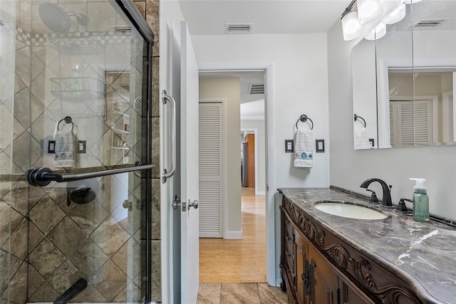 bathroom with a shower stall, visible vents, and vanity