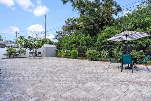 view of patio featuring a fenced backyard, a storage unit, outdoor dining area, and an outbuilding