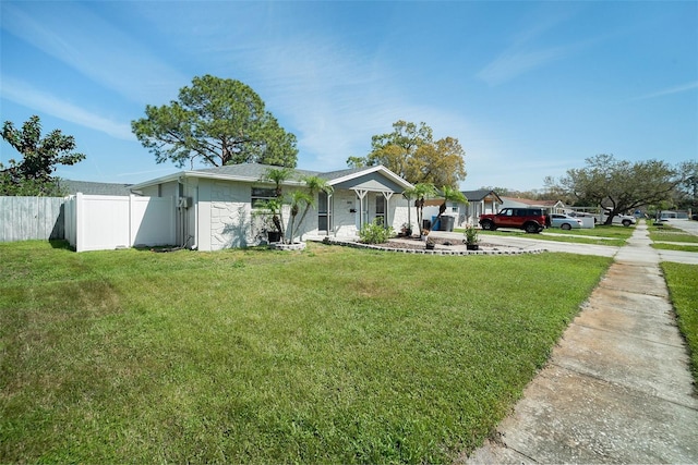 view of front facade with driveway, a front yard, and fence