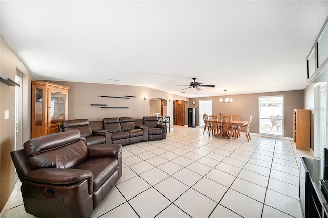 living area featuring arched walkways, light tile patterned floors, a chandelier, and baseboards