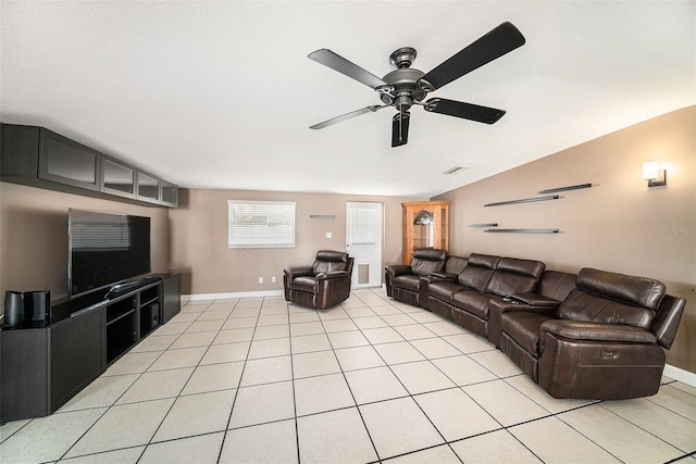 living area with light tile patterned floors, lofted ceiling, a ceiling fan, and baseboards