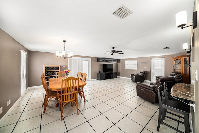 dining area featuring light tile patterned floors, baseboards, visible vents, and ceiling fan with notable chandelier