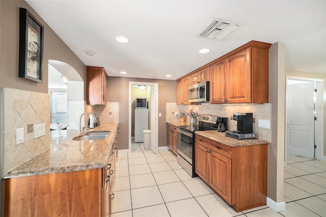 kitchen featuring brown cabinets, light tile patterned floors, visible vents, appliances with stainless steel finishes, and a sink